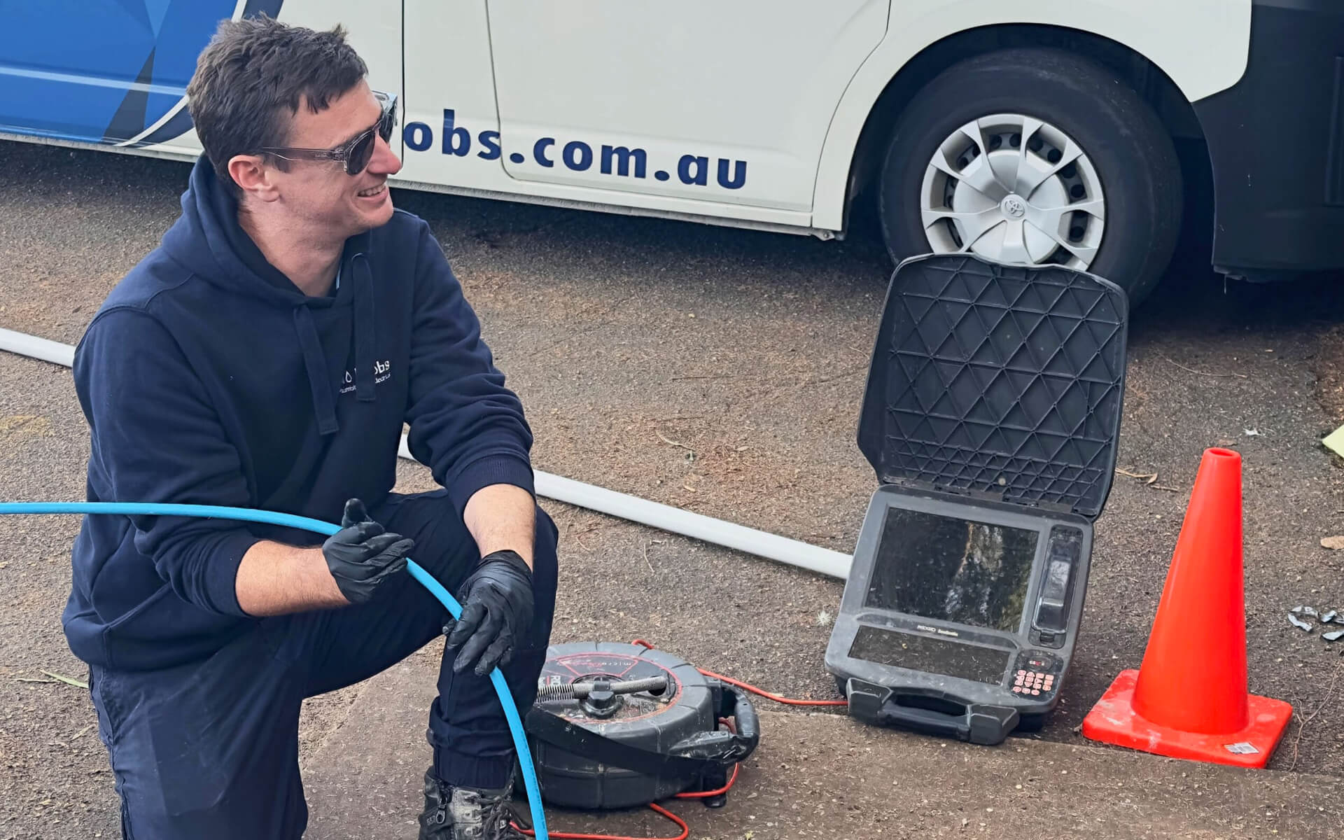 Technician using high-pressure drain cleaning equipment to clear a blocked drain.